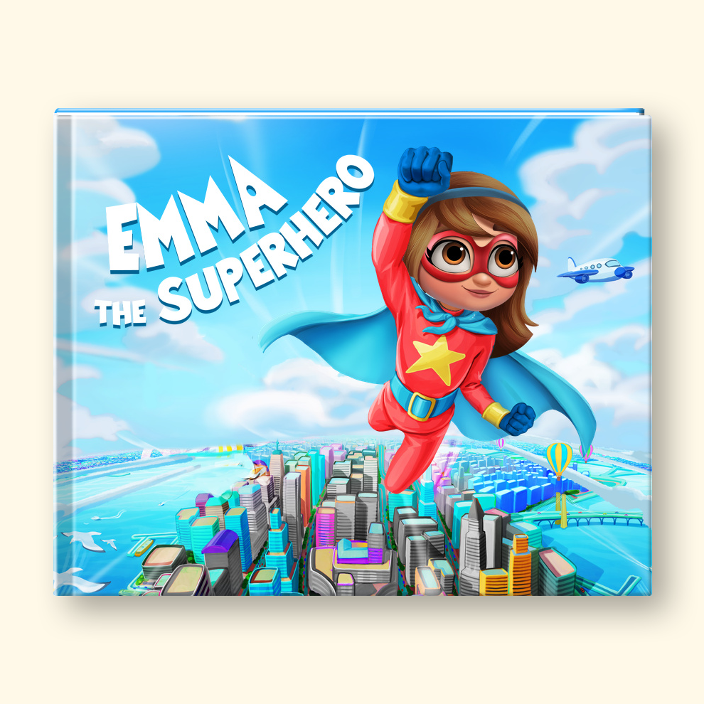 A hardcover children's book titled 'Emma the Superhero' featuring a colorful illustration of a girl superhero flying over a city skyline. The book is shown standing upright against a light cream background.